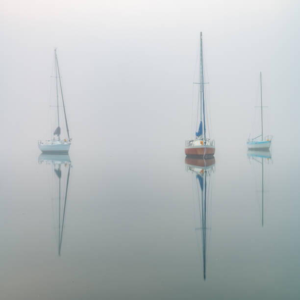 Enveloped in a dense fog boats appear through the mist over the bay. Koolewong on the Central Coast, NSW, Australia.