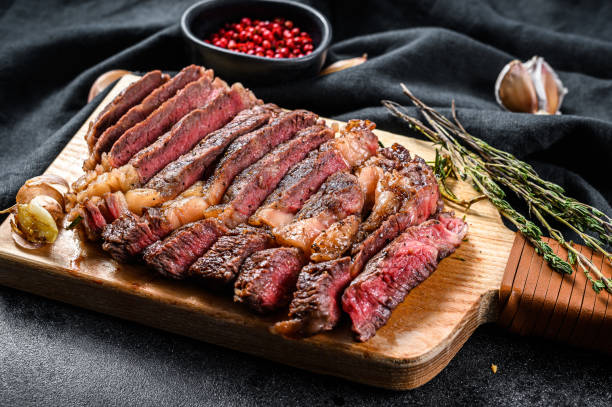 istock Sliced rib eye steak on a chopping Board, medium rare. black background. top view. Copy space 1274153287