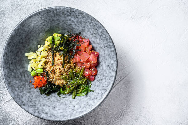 Poke bowl with raw tuna fish and vegetables. Hawaiian dish. Healthy eating concept. Gray background. Top view. Copy space