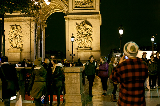 Paris, France - 12th december 2014: Tourists photograph the Arch of Triumph on a cold, rainy night (contains people).