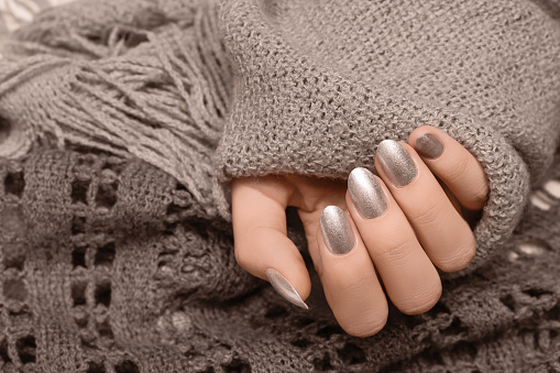 Female hands with gold nail design. Red nail polish manicured hands. Woman hands hold brown wool shawl