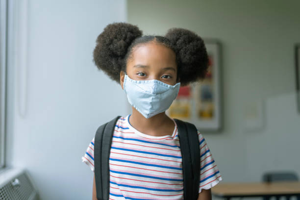 istock Elementary age girl wearing a protective face mask at school 1274273457
