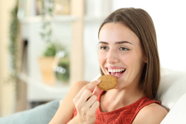 istock Happy woman is eating cereal cookie at home 1274287449