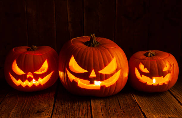 Pumpkins carved for Halloween on Rough Wood Table.