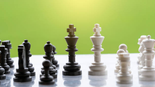 istock Black and white chess on board, strategic decisions and strategic movement concept with green blurred background. 1274325241