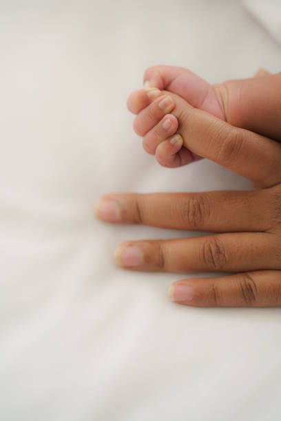 istock infant baby hand holding mom finger on white bed 1274372420