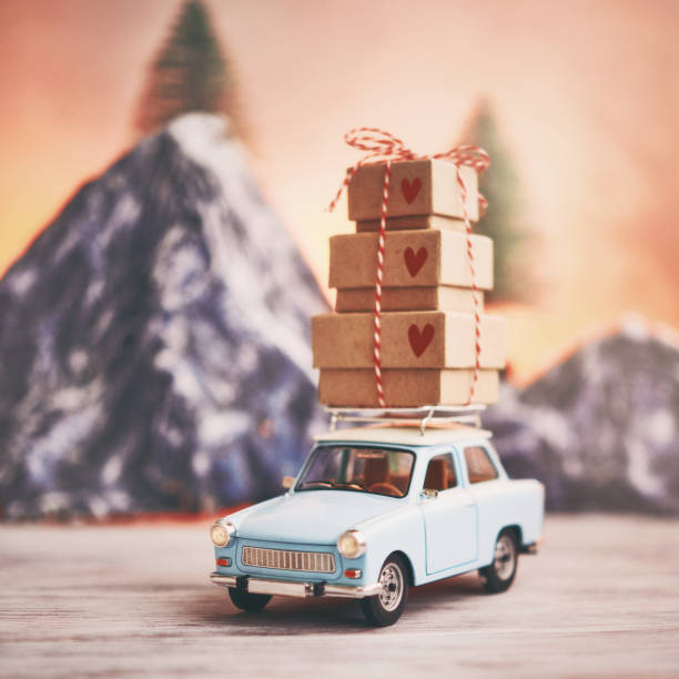 istock Little blue car with gift stack on roof rack in front of mountain range 1274394117