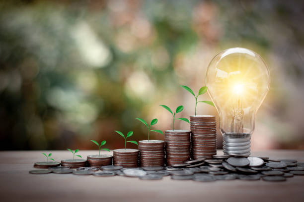istock Tree growing on stacks of coins and Energy saving light bulb with bokeh background. Saving money, accounting and financial concept. 1274606429