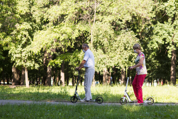 istock senior couple riding a scooters in the park. Active Seniors 1274607031