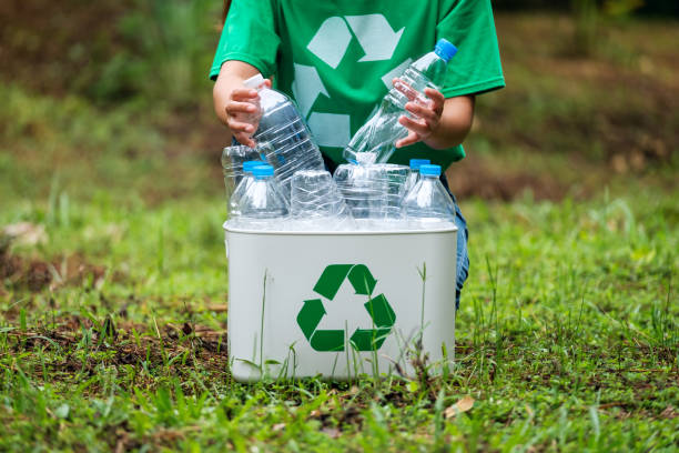 istock A woman collecting and putting plastic bottles into a recycle bin 1274642451