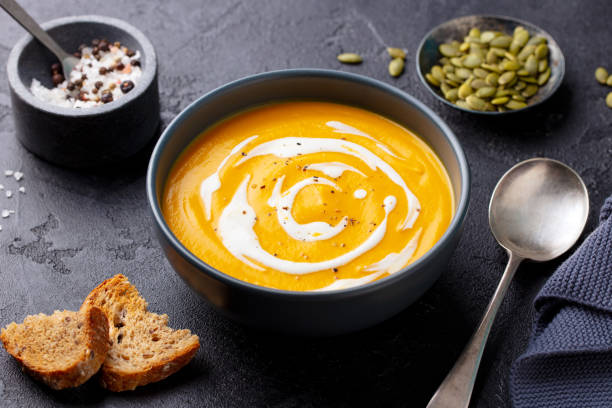 istock Pumpkin soup with cream in black bowl. Grey background. Close up. 1274688690