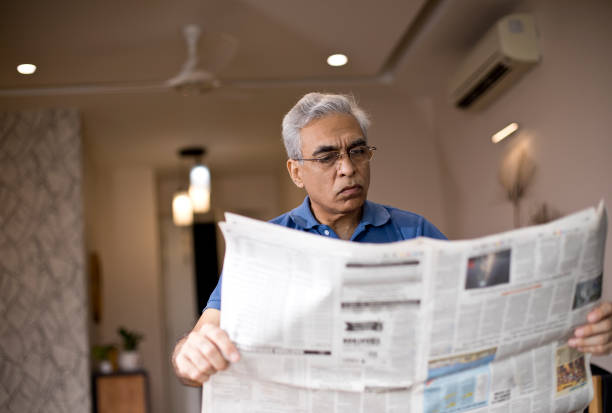 istock Senior man reading newspaper at home 1274688781