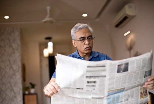 Senior man reading newspaper at home