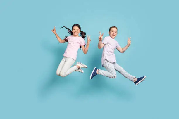 Photo of Full length body size view of her she his he nice attractive small little cheerful cheery friends friendship kids jumping showing v-sign having fun isolated over blue pastel color background