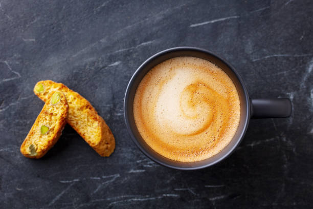 coffee espresso in cup with biscotti cookies on black marble background. close up. top view. - biscotti coffee cappuccino latté imagens e fotografias de stock