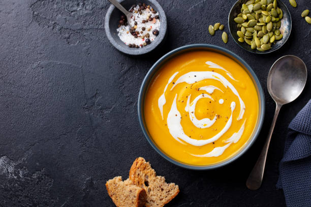 istock Pumpkin, butternut squash soup with cream in black bowl. Dark grey background. Copy space. Top view. 1274700237