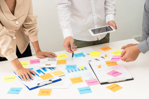 istock business people planning startup project placing sticky notes session to share idea on glass wall, Strategy Analysis Office Concept 1274705093
