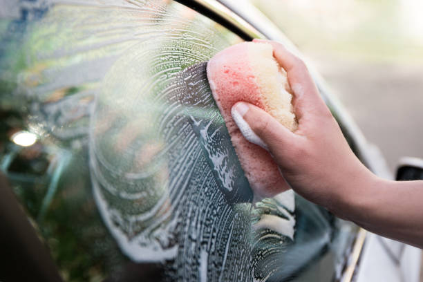handle car wash concept - male hand holding sponge and washing car window stock photo