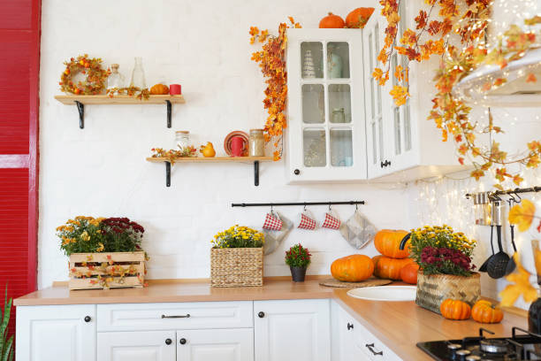 Autumn kitchen interior with pumpkin, fallen leaves, Thanksgiving dinner preparation Autumn kitchen interior with pumpkin, fallen leaves, Thanksgiving dinner preparation red kitchen cabinets stock pictures, royalty-free photos & images