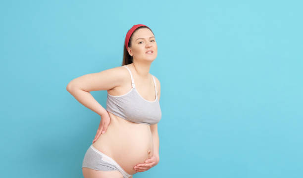 istock young pregnant woman on blue background, backache 1274728341