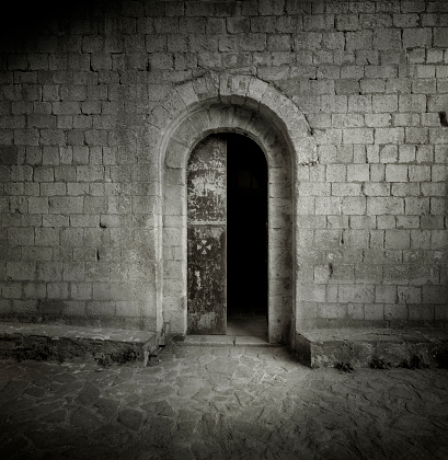 Medium format film photography shot. Black and white image of an old medieval gate with a stone wall around.