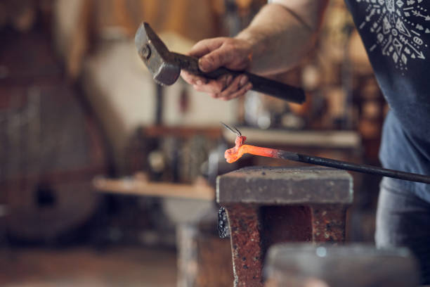 istock Blacksmith manually forging on iron on anvil at forge. Treatment of molten metal close-up. 1274740109