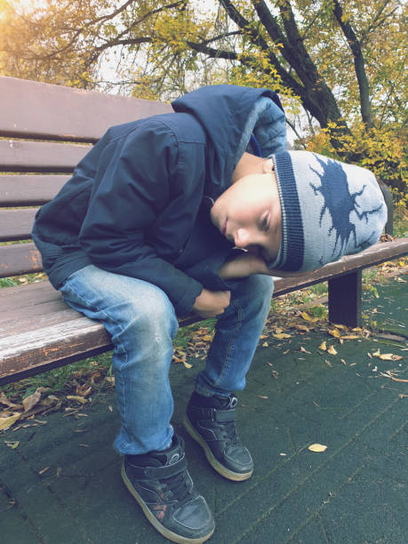 istock sad boy sitting on bench alone outdoor 1274741227