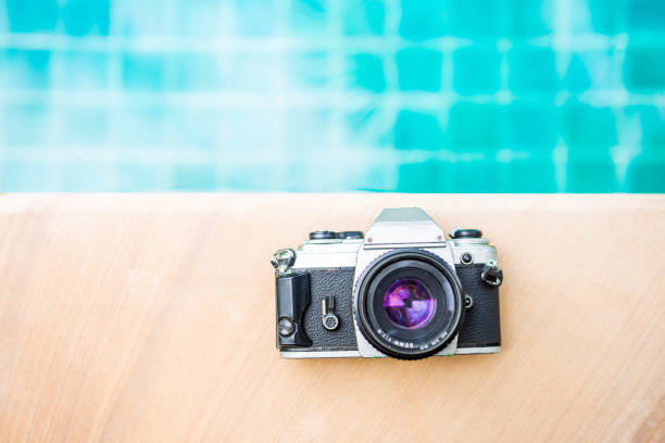 istock Old film camera on swimming pool edge with space on blue water background 1274748354