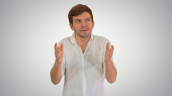 Medium shot. Front view. Excited young man in casual clothes looking into camera telling a story and gesturing on gradient background. Professional shot in 4K resolution. 047. You can use it e.g. in your medical, commercial video, business, presentation, broadcast
