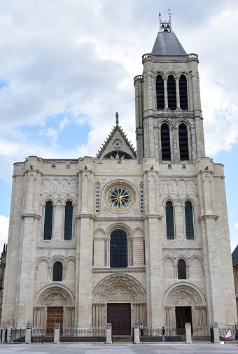 Paris, France. View of the Basilique Saint-Denis, the first gothic church. West Facade and bell tower with blue sky and clouds.