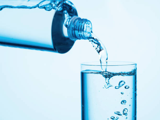istock Pouring water from a bottle into glass on a blue background. 1274787139