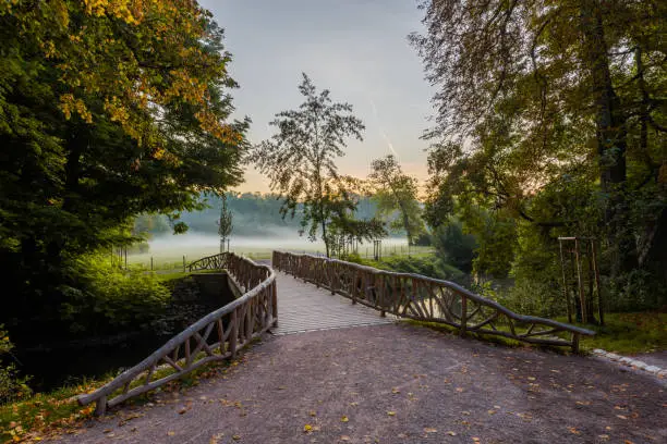 Bridge over the river Ilm for pedestrians in Weimar in the park on the Ilm in the morning in autumn with fog