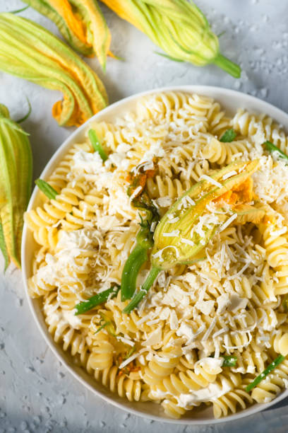 makaron fusilli z serem ricotta i kwiatami cukinii (fiori di cukinie). włoskie przepisy kulinarne - squash flower zdjęcia i obrazy z banku zdjęć