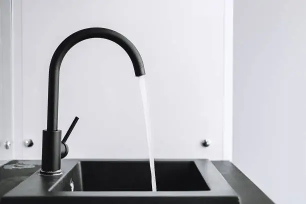 A running tap with the water running in the kitchen. The tap lets the water run, nobody. High quality photo