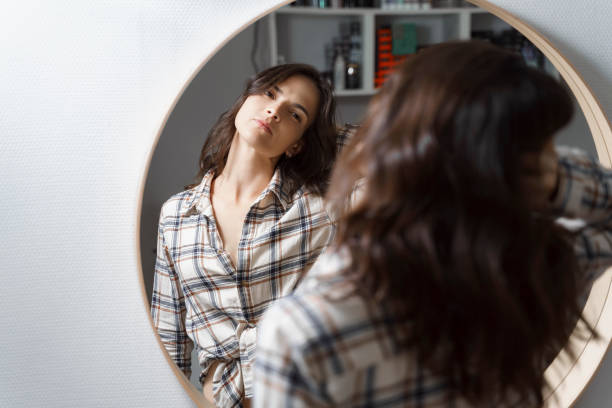 istock beautiful young woman looking in the mirror 1274845332