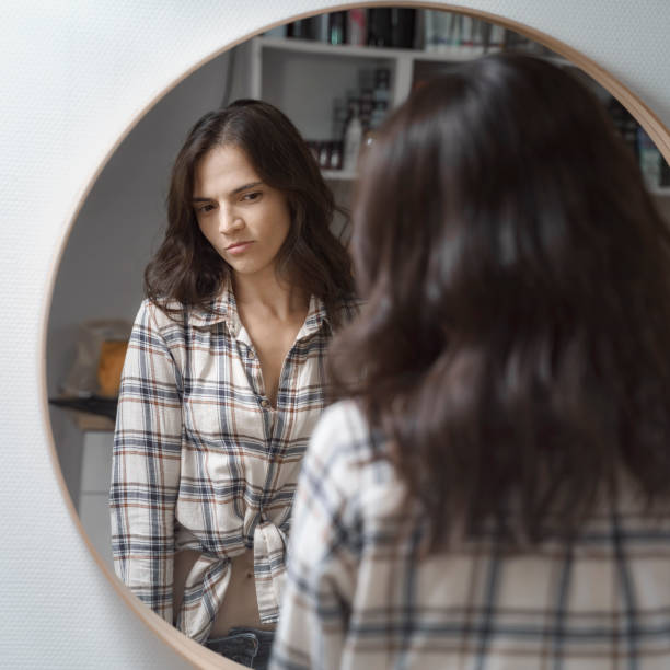 istock beautiful young woman looking in the mirror 1274845377