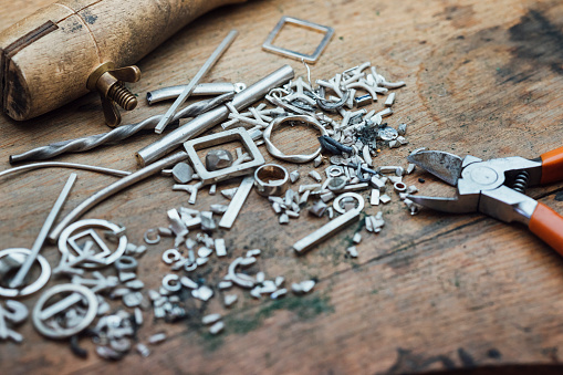 A close-up of scrap pieces of silver and metal on a workbench from a jeweler crafting jewelry. / Female Focus Collection