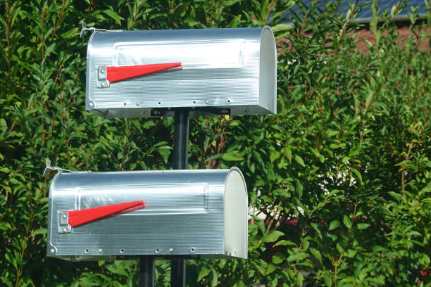 zwei altmodische außenpostfächer vor einer grünen hecke - mailbox mail box side view stock-fotos und bilder
