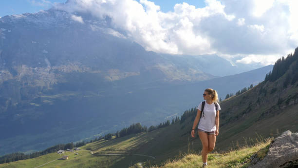 istock Young woman hikes through alpine meadow, at sunrise 1274852196
