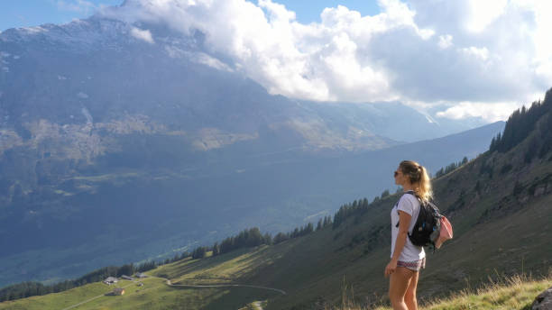 istock Young woman hikes through alpine meadow, at sunrise 1274852216