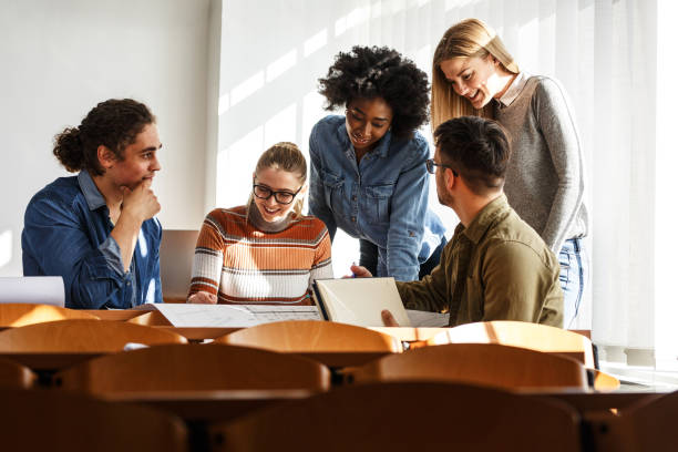 istock Group of design students sitting in classroom and examining blueprint homework project. 1274853222