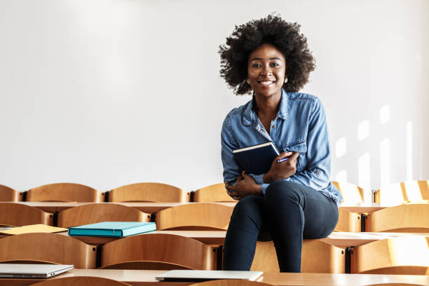 Young black female student sitting in classroom and preparing for final test. stock photo