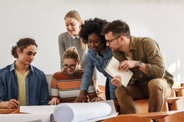 istock Group of design students sitting in classroom and examining blueprint homework project. 1274855274