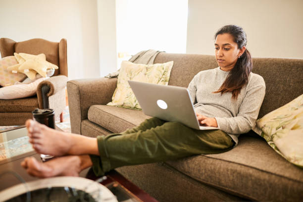 istock Young woman using a laptop while relaxing at home 1274865573