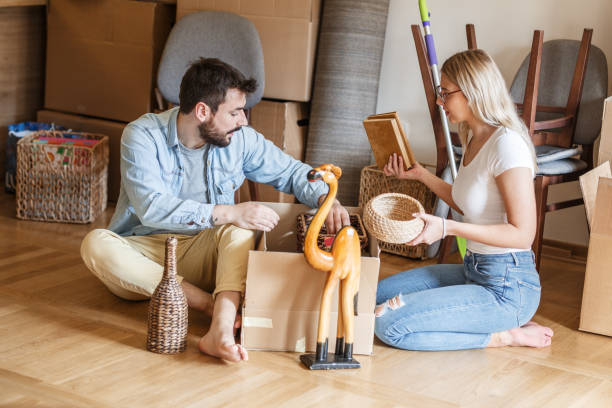 istock Married couple unpacking cardboard boxes at new home. 1274867438
