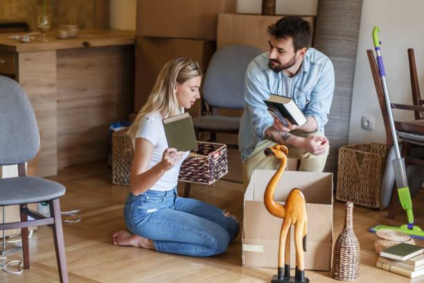 istock Married couple unpacking cardboard boxes at new home. 1274867455