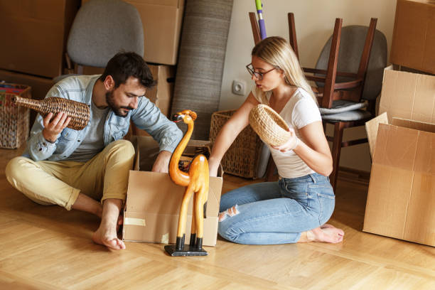 Married couple unpacking cardboard boxes at new home.