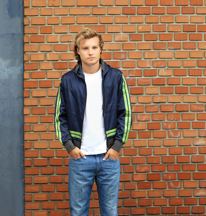 Handsome young man standing against brick wall background
