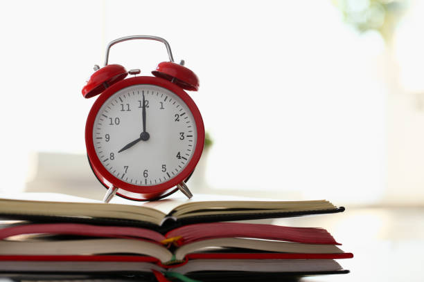 istock Red alarm clock standing on pale of books 1274934372