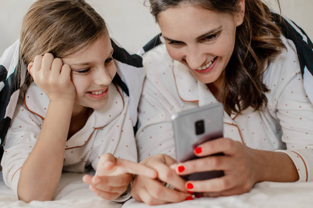 istock Mother and daughter using mobile phone in bed 1274949429